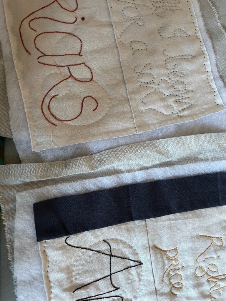 Pieces of quilted and decorated textile in pieces, with a join ready to be made with some grey fabric.