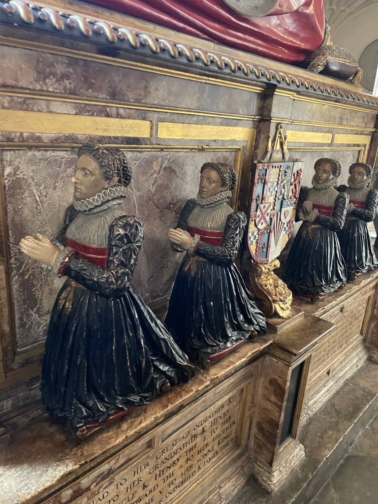 Four female figures dressed in black are shown on a tomb kneeling in prayer.