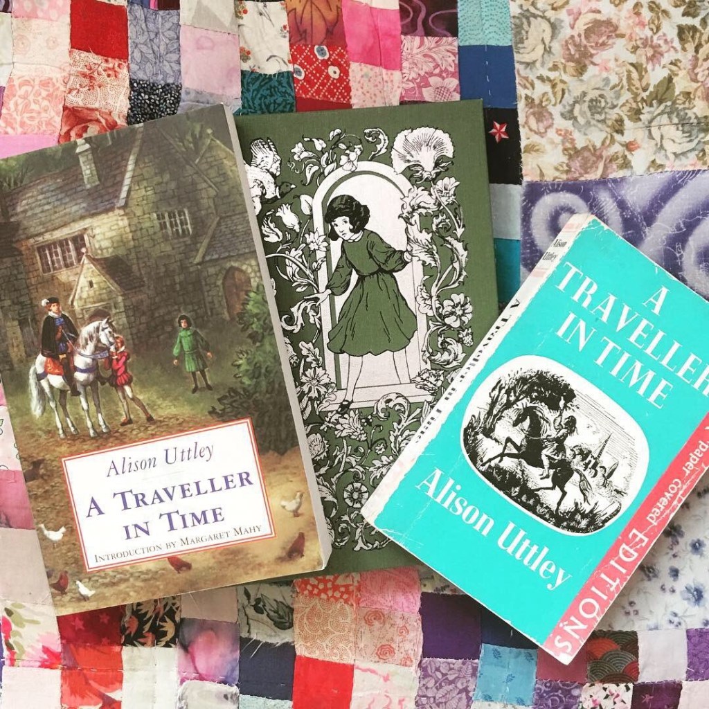 Three copies of A Traveller in Time by Alison Uttley resting on a patchwork cushion.