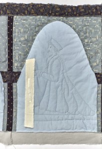 A quilted picture of Gregory Cromwell, kneeling under an arch and holding a book. A strip of fabric with text attached falls from the book. 